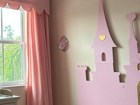 Pared de un cuarto infantil con cortinas rosadas y un castillo de madera rosado